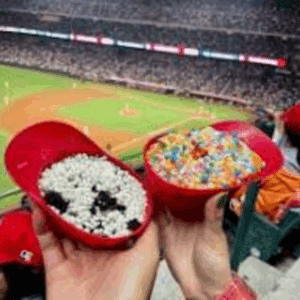 Hands holding snacks at baseball game.